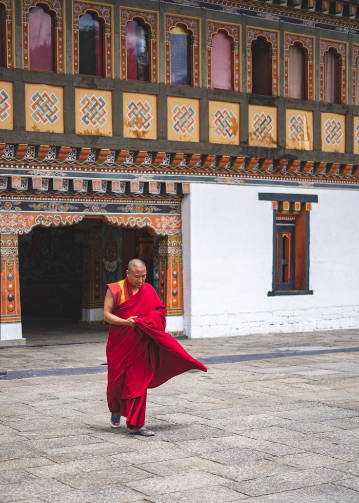 Mastering the First Impression: Your intriguing post title goes here A monk in traditional attire walks through a beautifully decorated Bhutanese monastery, showcasing cultural and spiritual heritage.